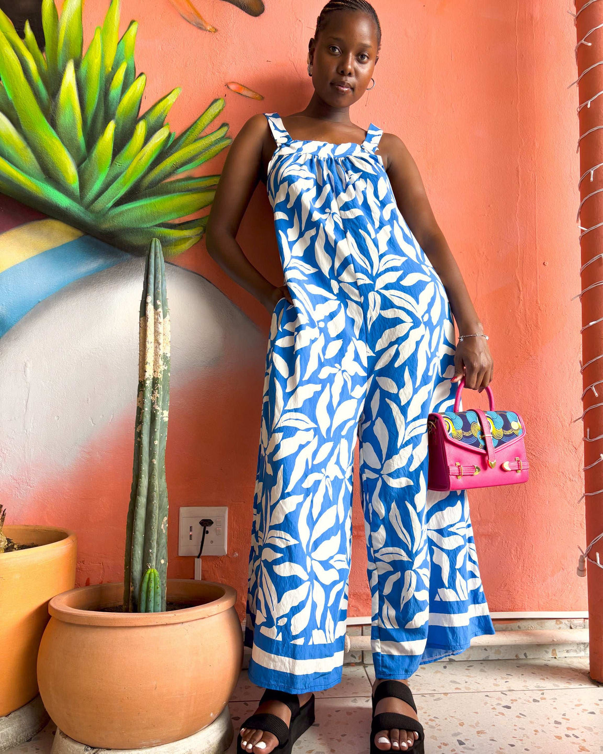 African woman wearing a Kitsi Jumpsuit in blue and white, with a Dr Pachanga handbag.