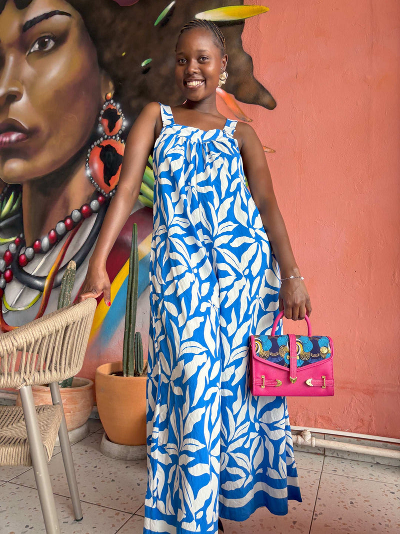 Smiling African woman wearing a Kitsi Jumpsuit in blue and white, with a Dr Pachanga handbag.