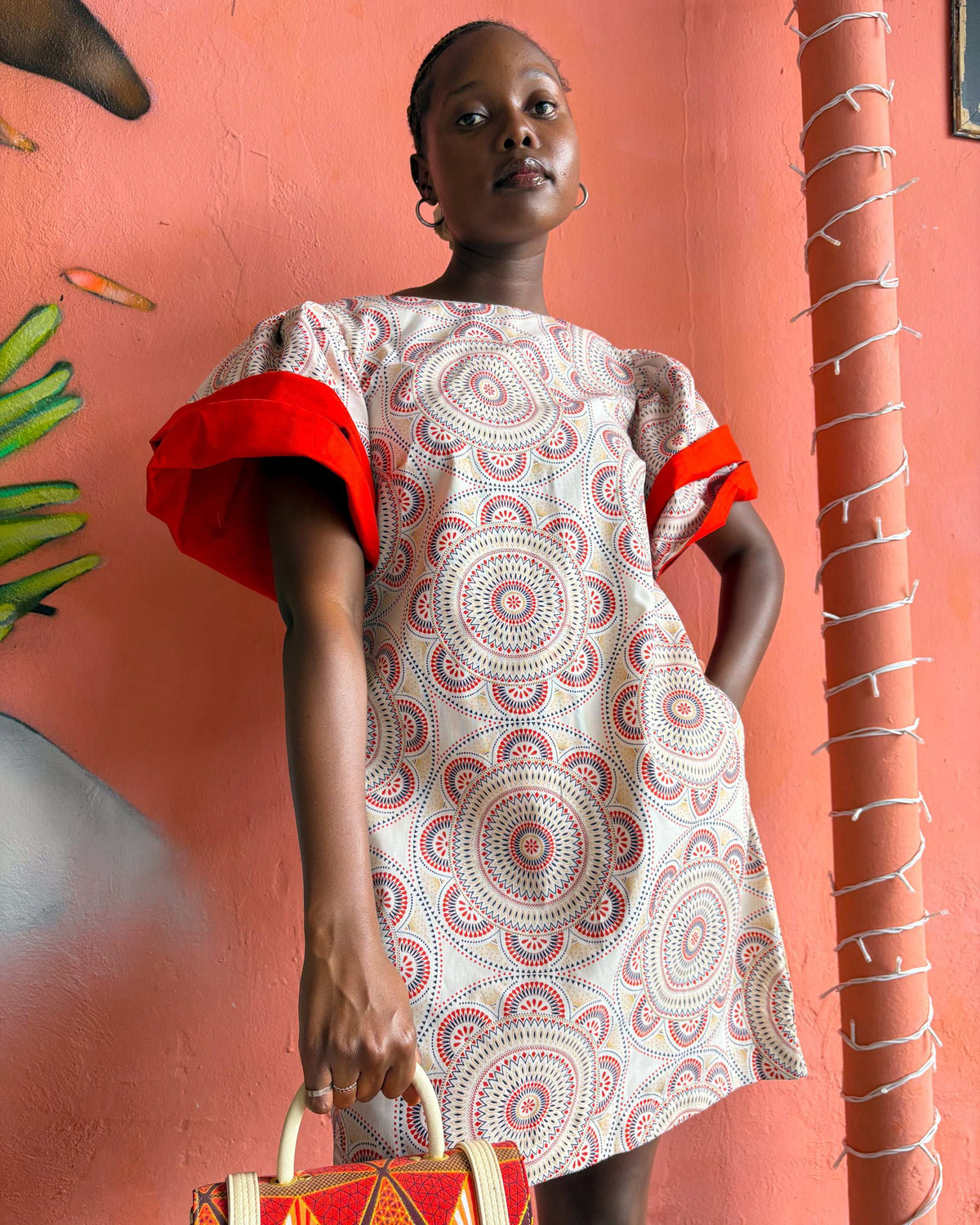 Close up, African woman wearing a Sam Dress in off white and red, with a Dr Pachanga handbag.