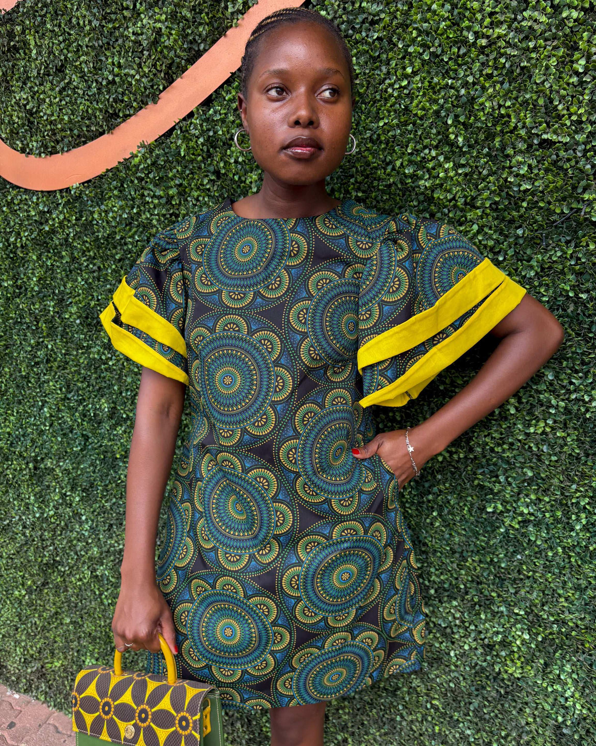 Smiling African woman wearing a Sam Dress in green, with a Dr Pachanga handbag.