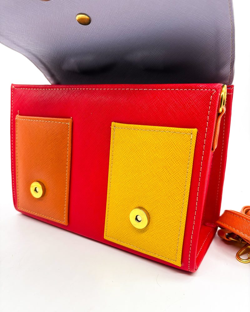 Open, electric red vegan leather handbag or crossbody bag, with African Wax fabric inlay, two gold buckles and a magnetic clasp.