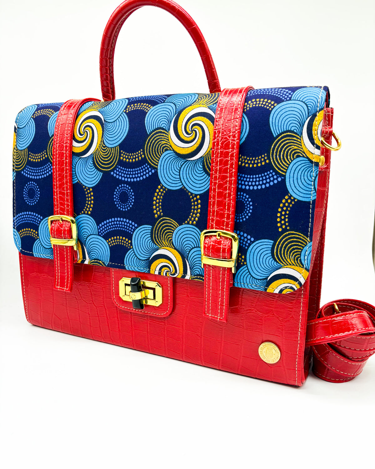 Red vegan leather handbag or backpack with gold and blue African wax fabric inlay, two gold buckled clasps and gold twist-lock.