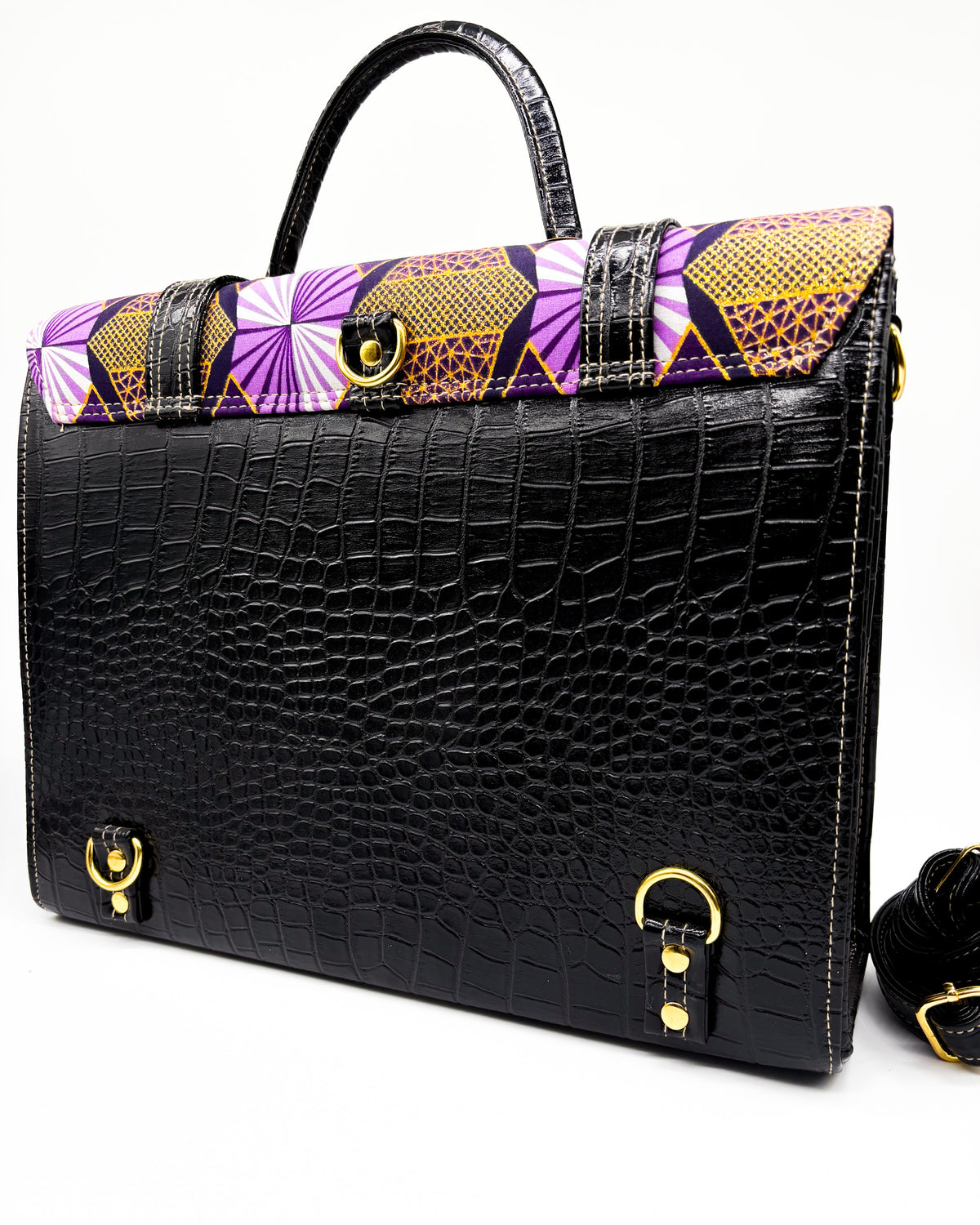 Back angle, black vegan leather handbag or backpack with purple and yellow African wax fabric inlay, two gold buckled clasps and a gold twist-lock.