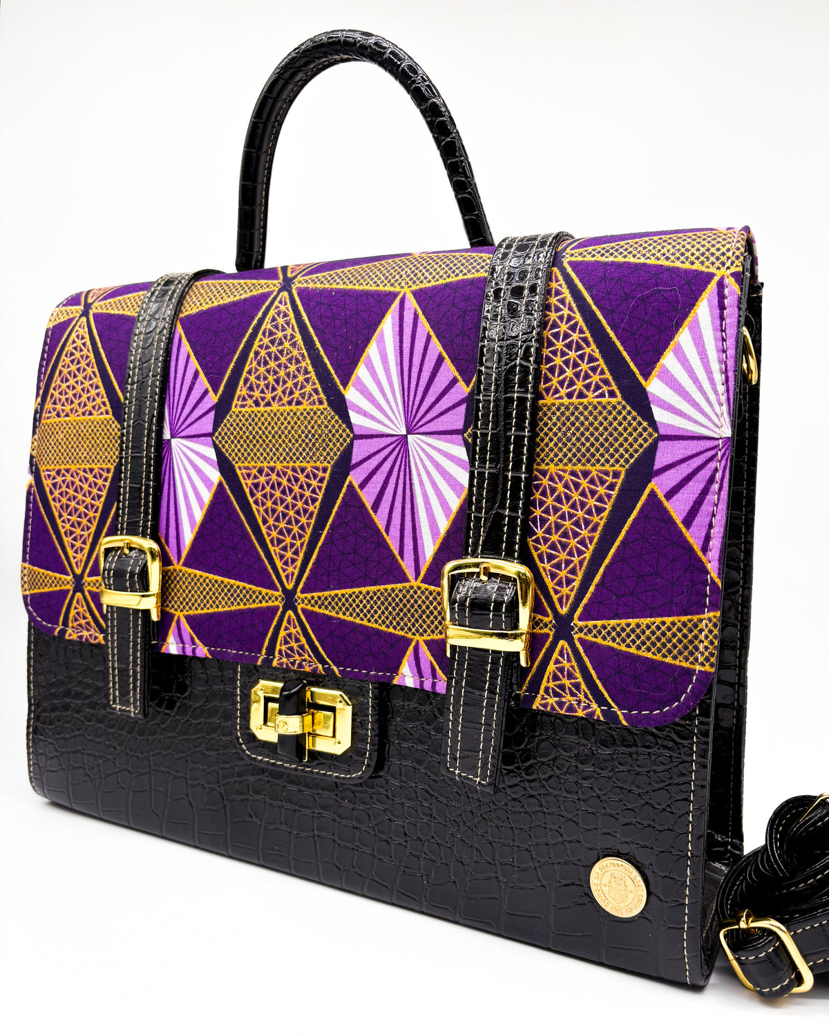 Front angle, black vegan leather handbag or backpack with purple and yellow African wax fabric inlay, two gold buckled clasps and a gold twist-lock.