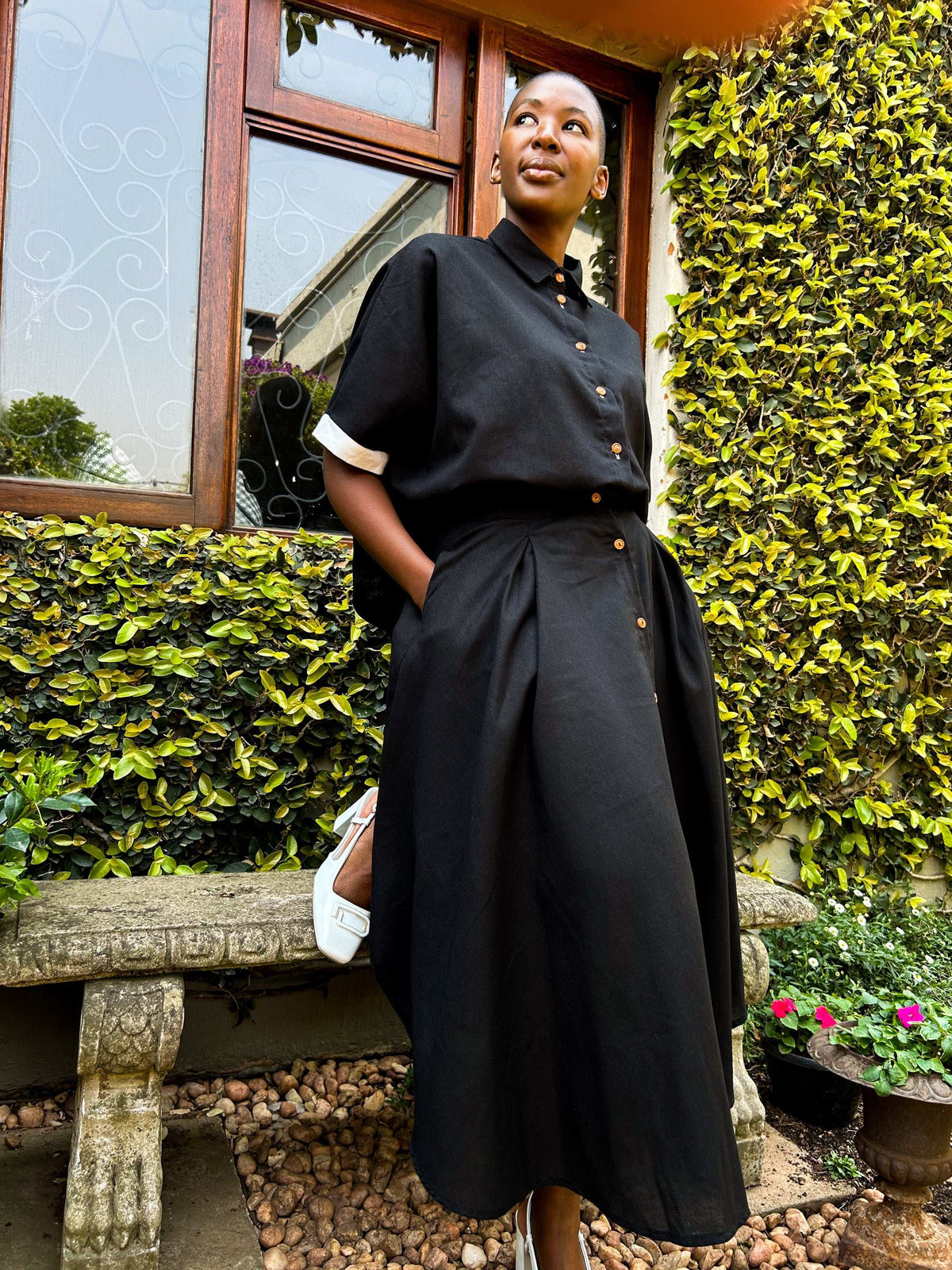 African woman wearing a Zandi Skirt in black with hands in her pockets.