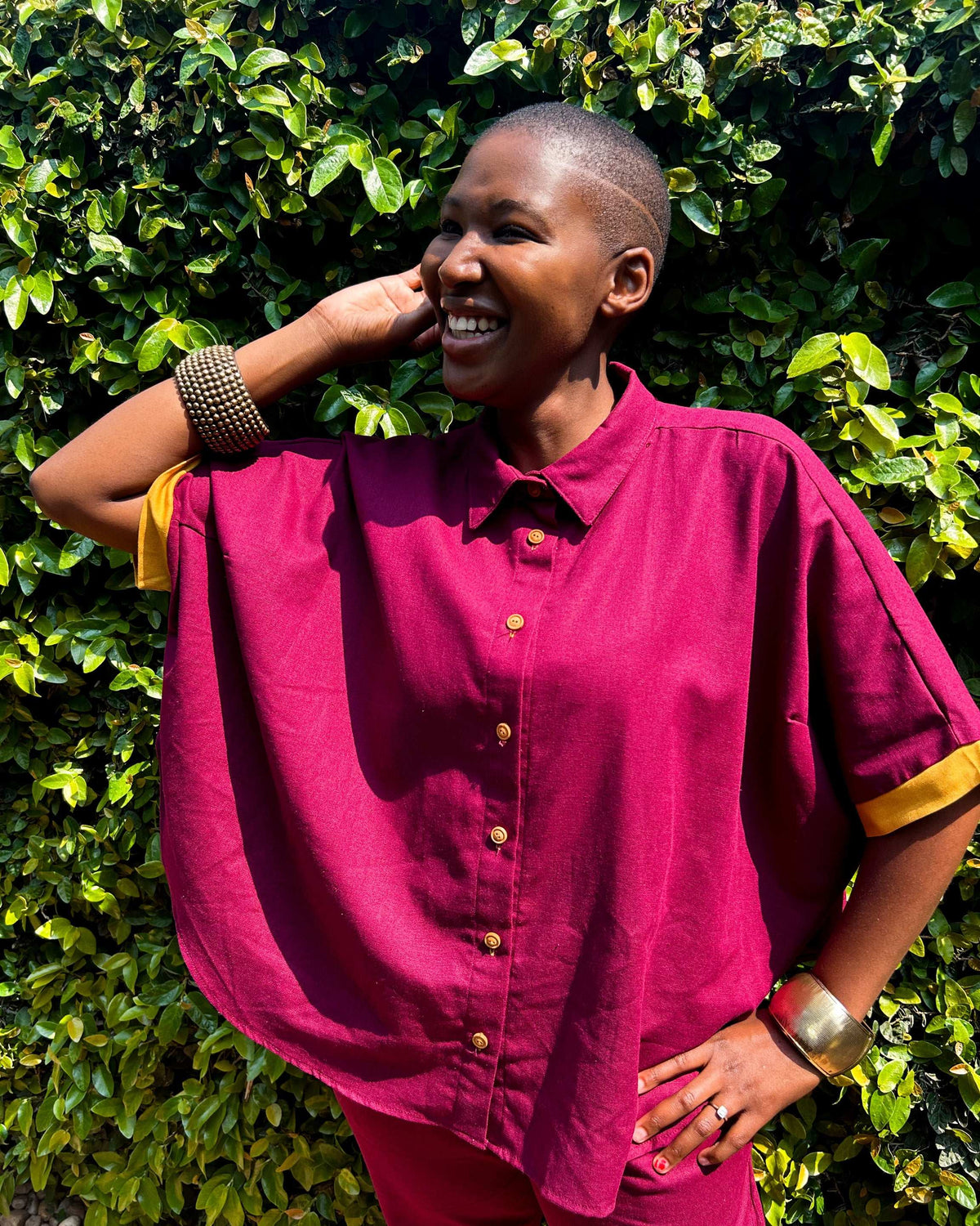 Close-up, smiling African woman wearing a maroon and mustard Marcelle Top.