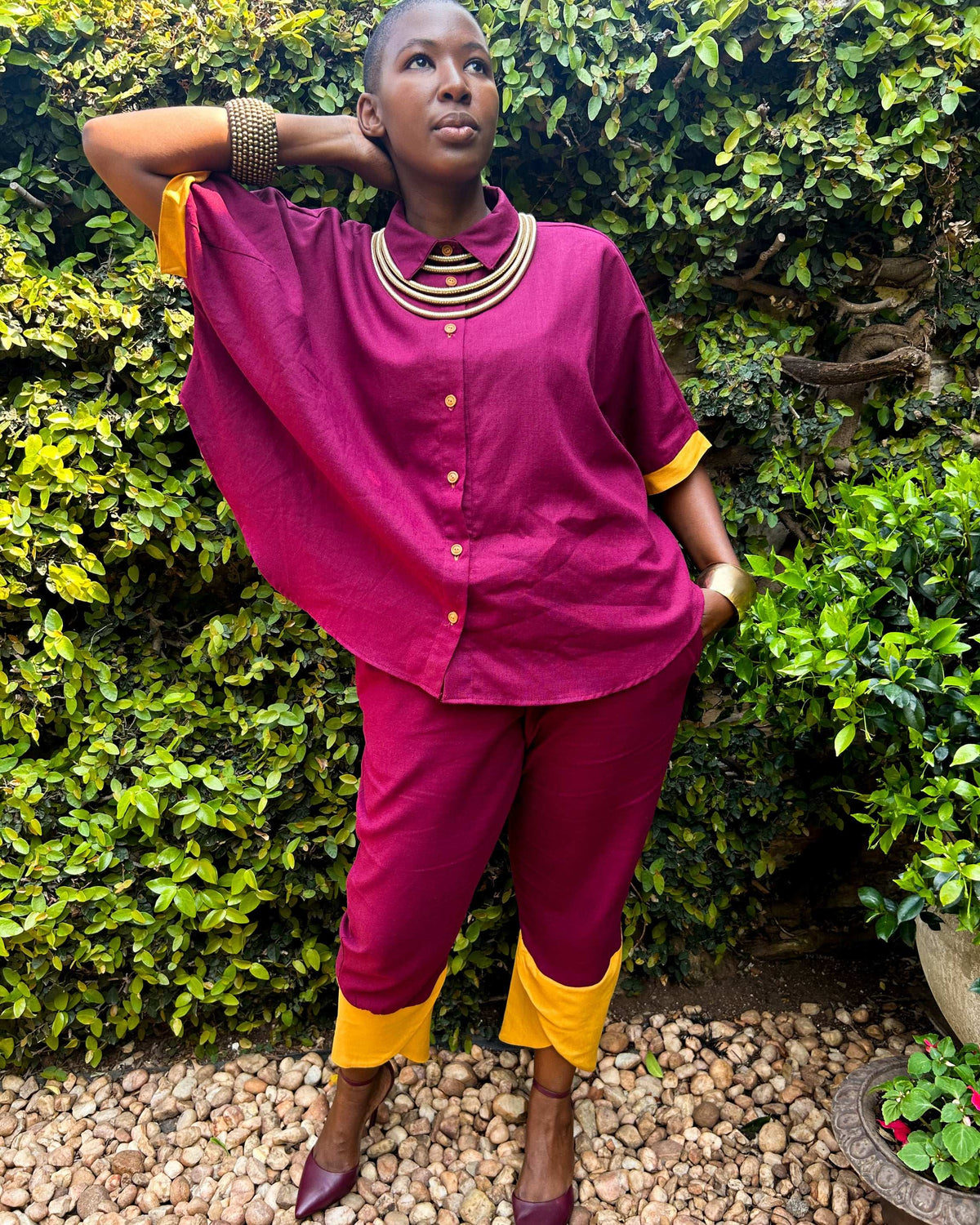 African woman wearing Dr Pachanga two-tone Kate Pants in maroon and yellow, with high heels.