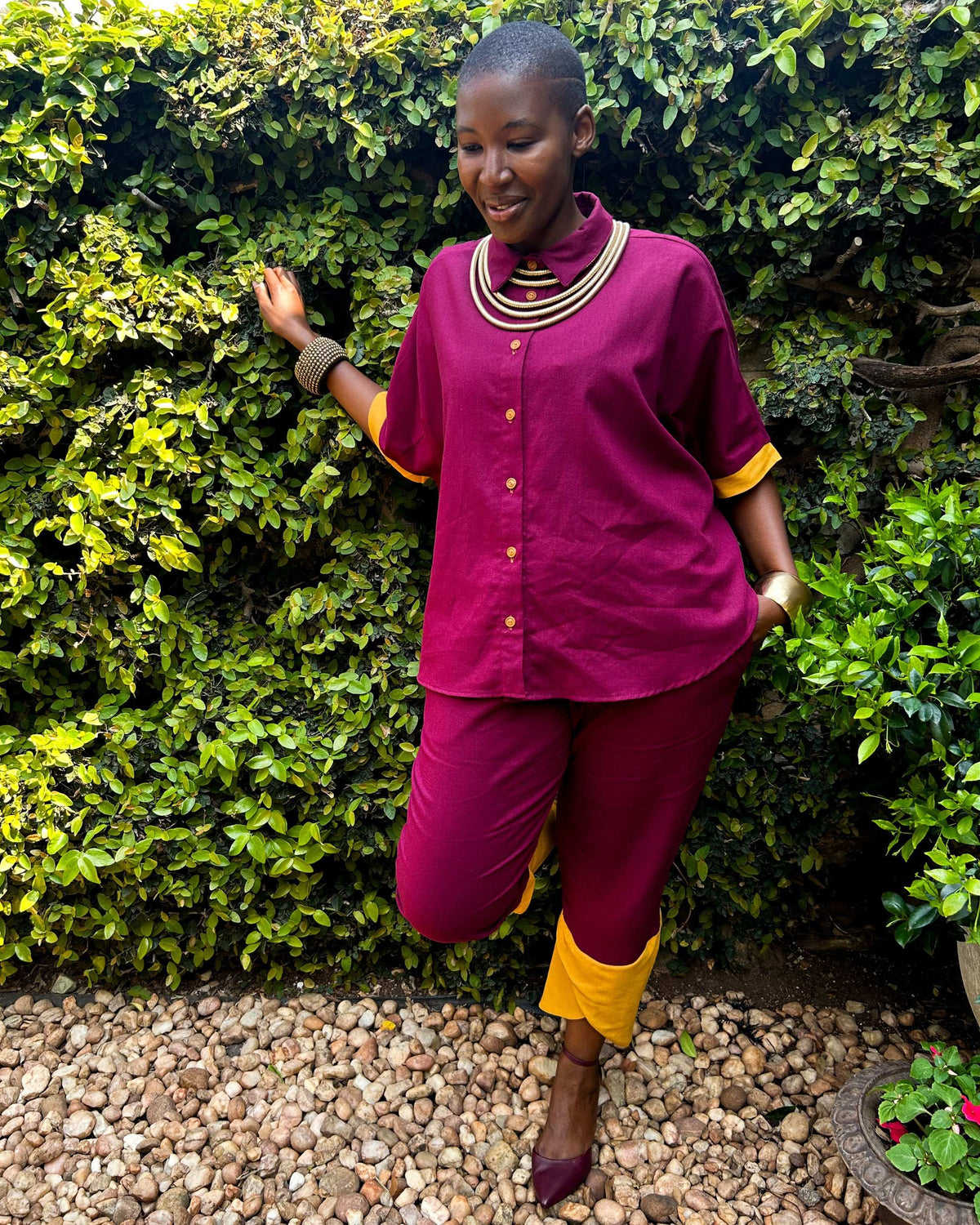 African woman wearing Dr Pachanga two-tone Kate Pants in maroon and yellow, with a hand in her pocket.