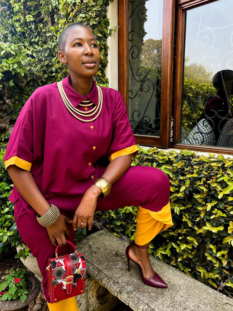 African woman wearing two-tone Kate Pants in maroon and yellow, with Dr Pachanga handbag.