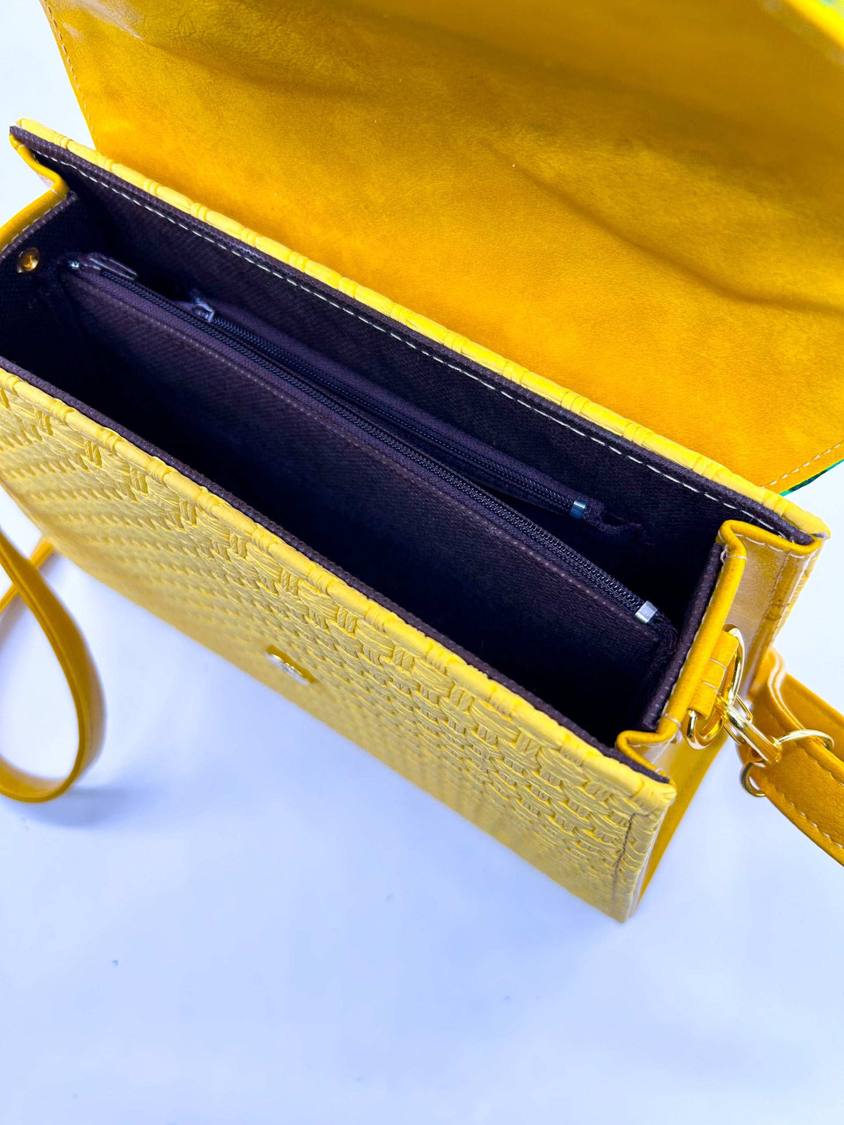 Inside view, yellow textured vegan leather handbag with green and red African Gold Wax fabric inlay, a magnetic clasp and adjustable strap.