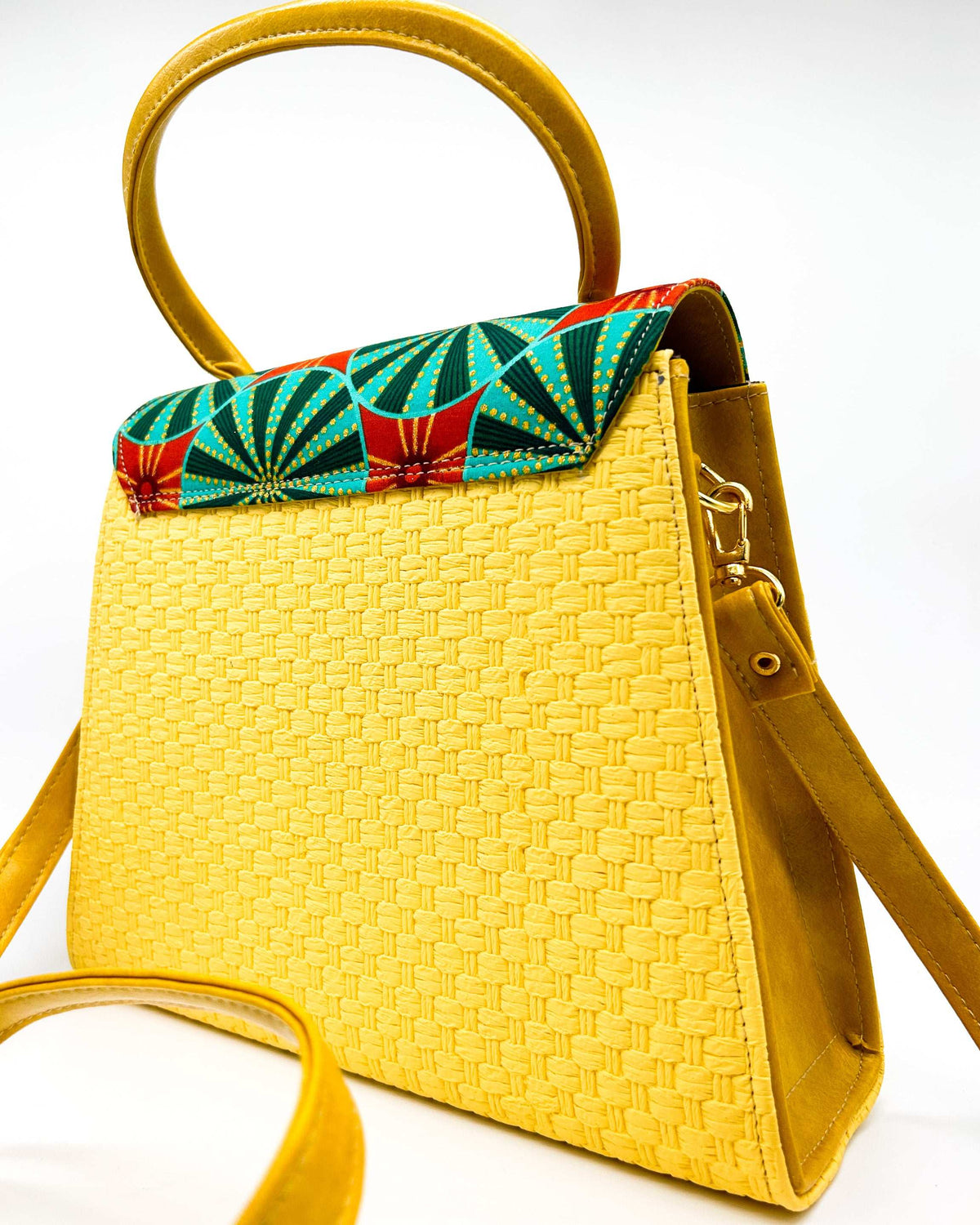 Back view, yellow textured vegan leather handbag with green and red African Gold Wax fabric inlay, a magnetic clasp and adjustable strap.