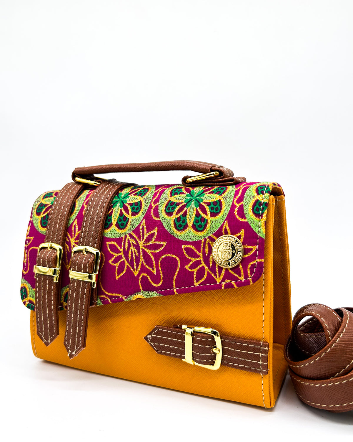 Orange vegan leather handbag with maroon and green African Gold Wax fabric inlay, three gold buckles and adjustable strap.