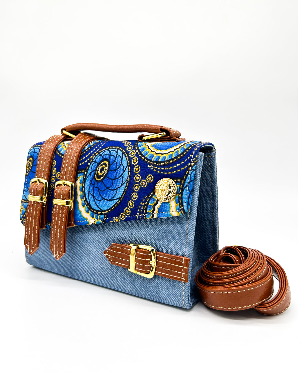 Blue denim coloured vegan leather handbag with blue and yellow African Gold Wax fabric inlay, three gold buckles and adjustable strap.