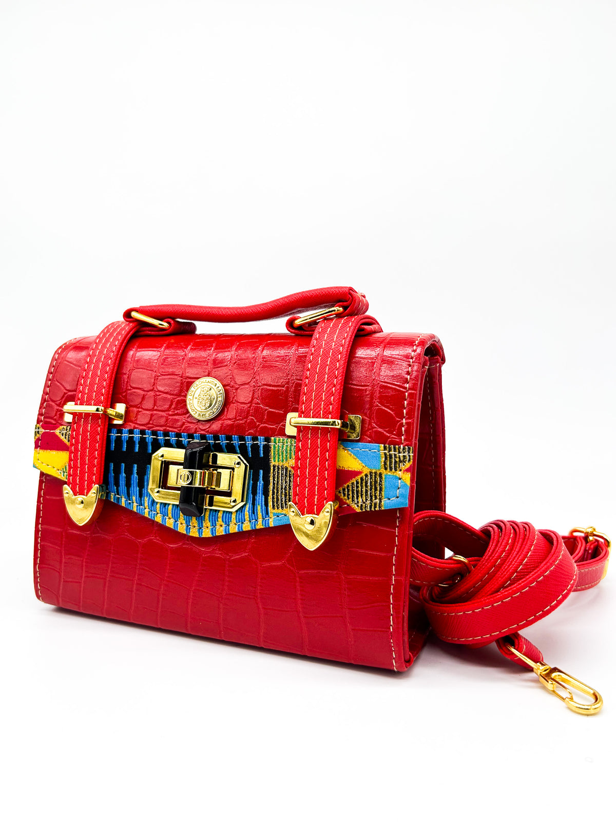 Red textured vegan leather clutch bag with colourful African Gold Wax fabric inlay, two gold buckles, a twist-lock clasp and adjustable strap.