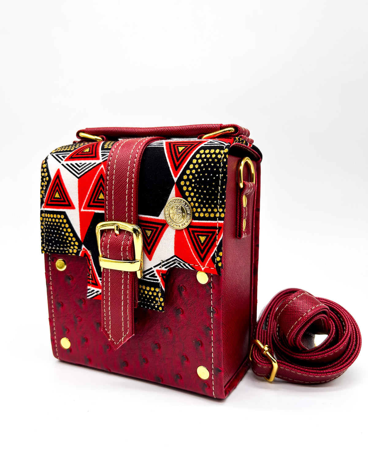 Maroon vegan leather handbag with yellow and red African Gold Wax fabric inlay, a single gold buckle, magnetic clasp and adjustable strap.