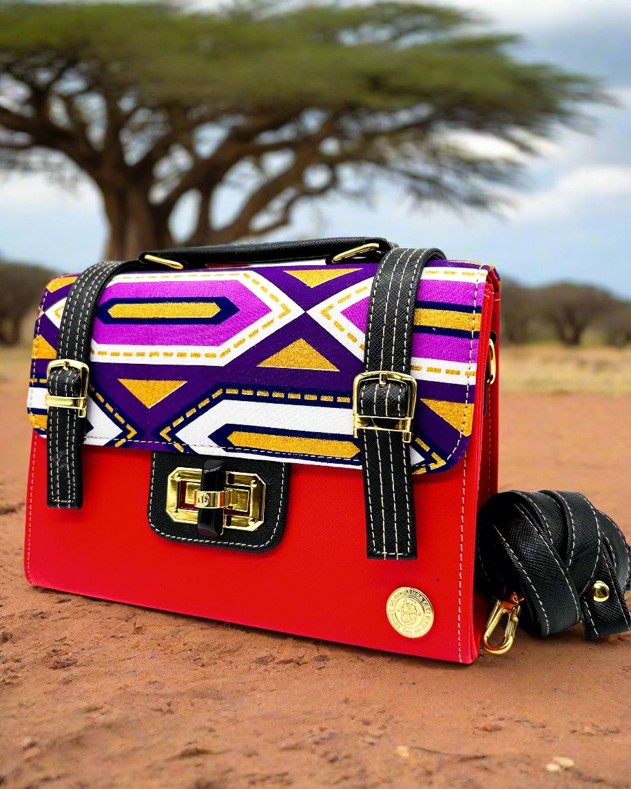 Nature setting, red vegan leather handbag with colourful African Gold Wax fabric inlay, two gold buckled straps, a twist-lock clasp and adjustable strap.