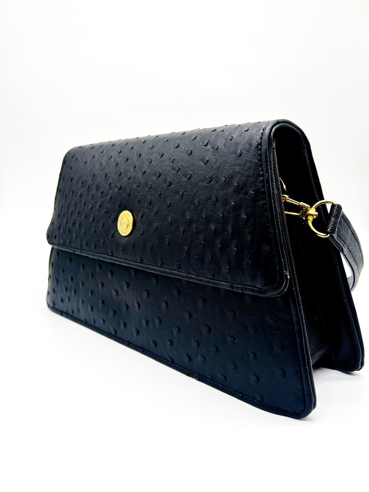 Black textured vegan leather handbag with a gold magnetic clasp and adjustable strap.