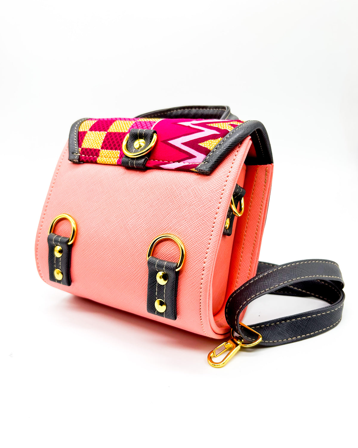 Back angle, salmon pink and black vegan leather handbag or backpack with gold African wax fabric inlay and two buckled clasps.