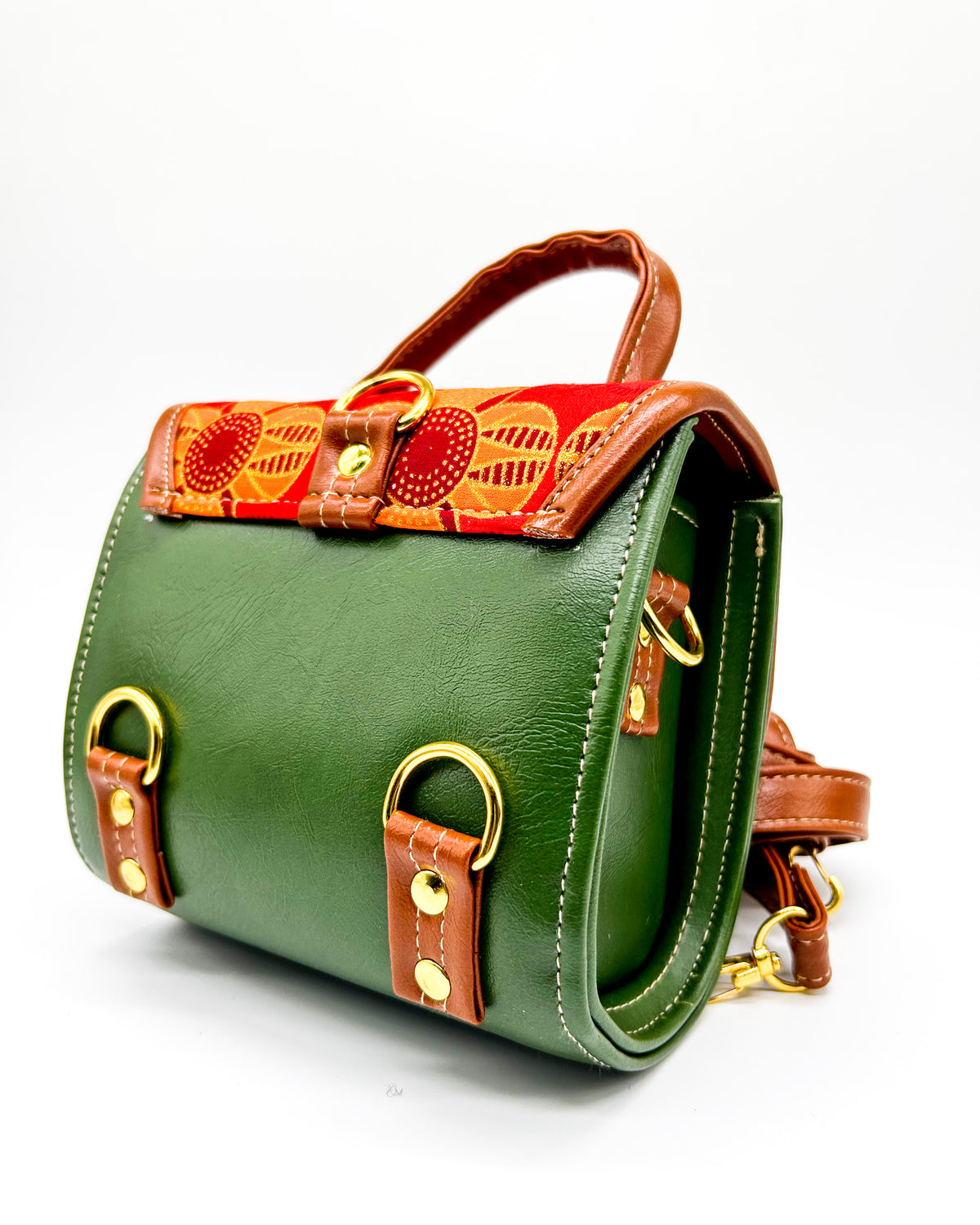 Back angle, olive green vegan leather handbag or backpack with red and orange African wax fabric inlay and two buckled clasps.