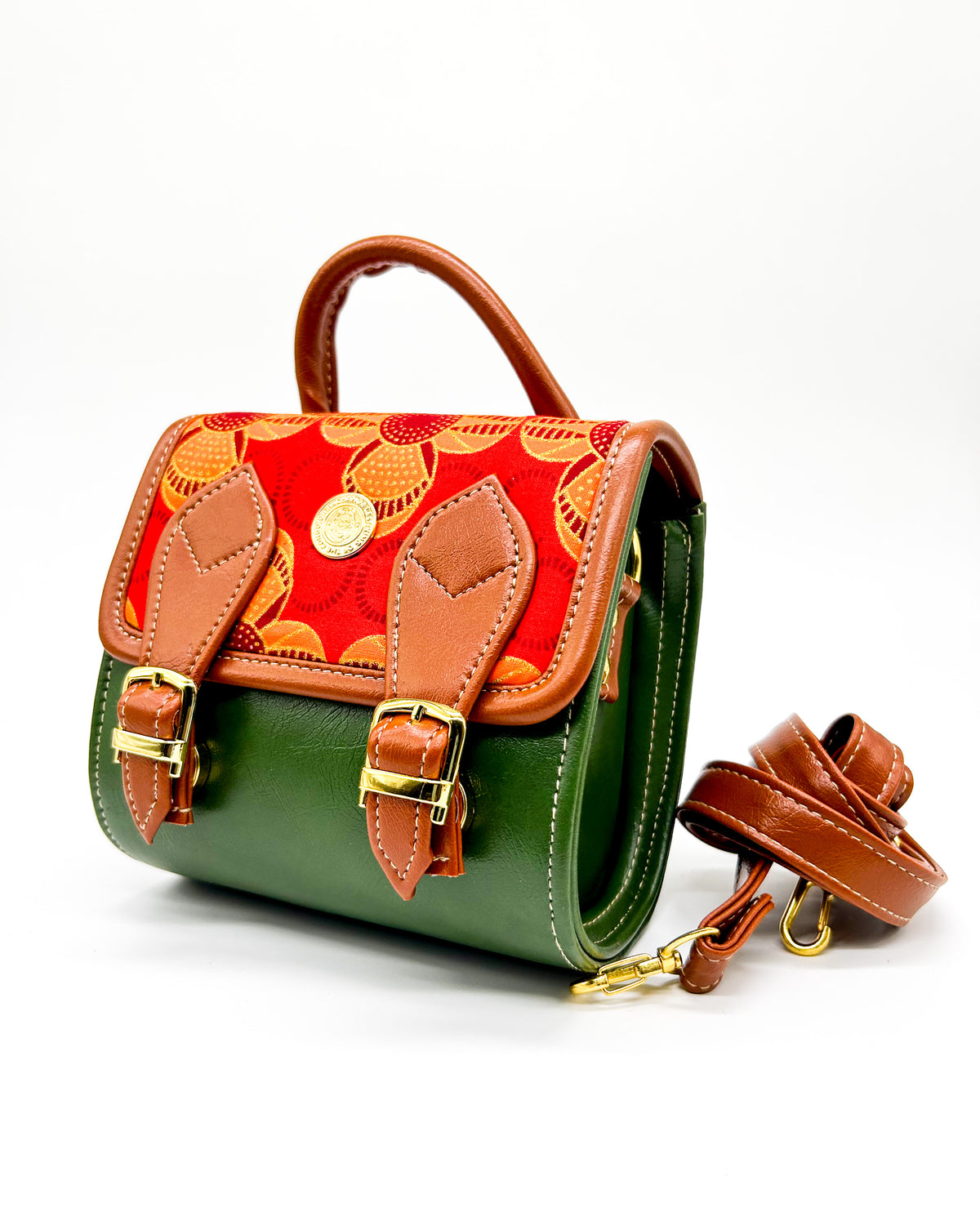 Olive green vegan leather handbag or backpack with red and orange African wax fabric inlay and two buckled clasps.