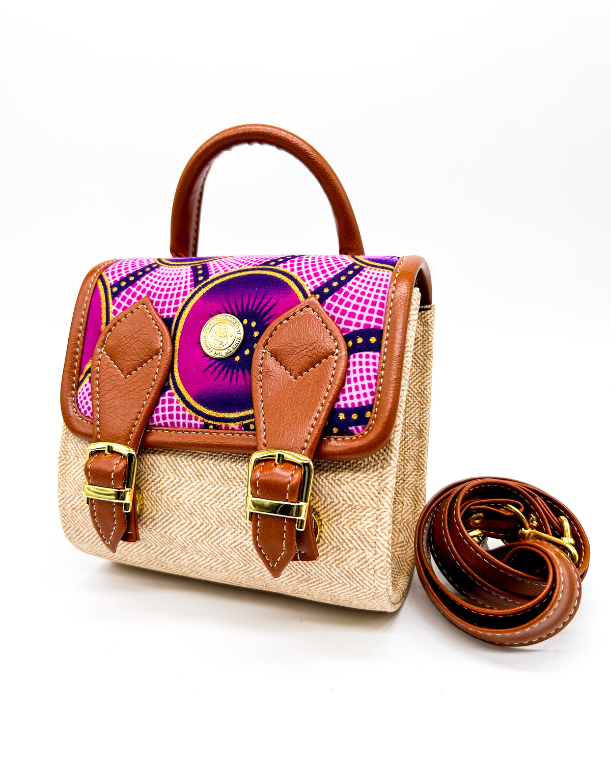 Front angle, beige vegan leather handbag or backpack with pink and yellow African wax fabric inlay and two buckled clasps.