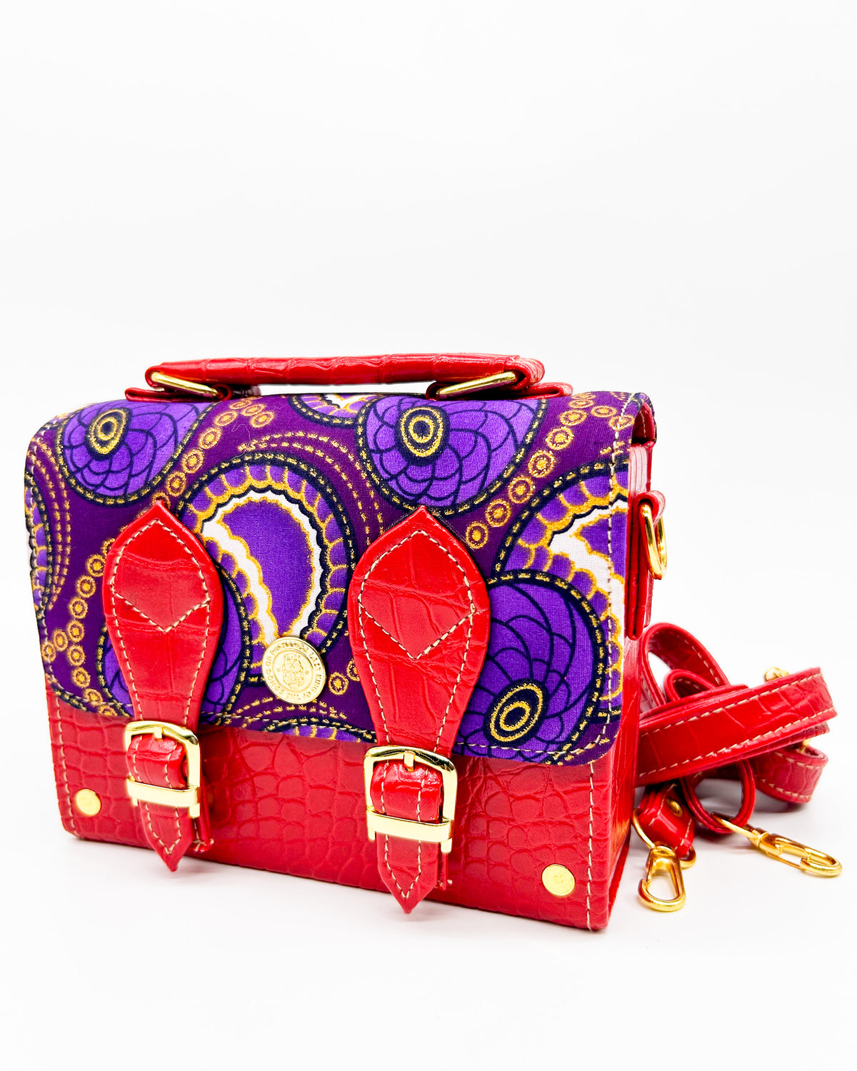 Red vegan leather handbag, backpack or crossbody bag with purple and yellow African wax fabric inlay and two gold buckled clasps.