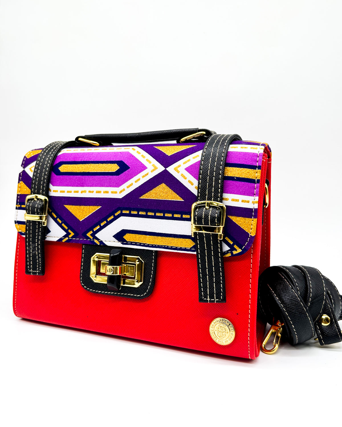 Red vegan leather handbag with colourful African Gold Wax fabric inlay, two gold buckled straps, a twist-lock clasp and adjustable strap.