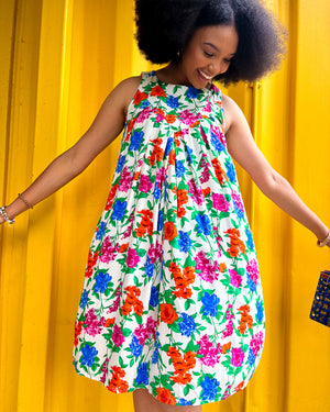 Woman wearing a colorful floral dress against a yellow background