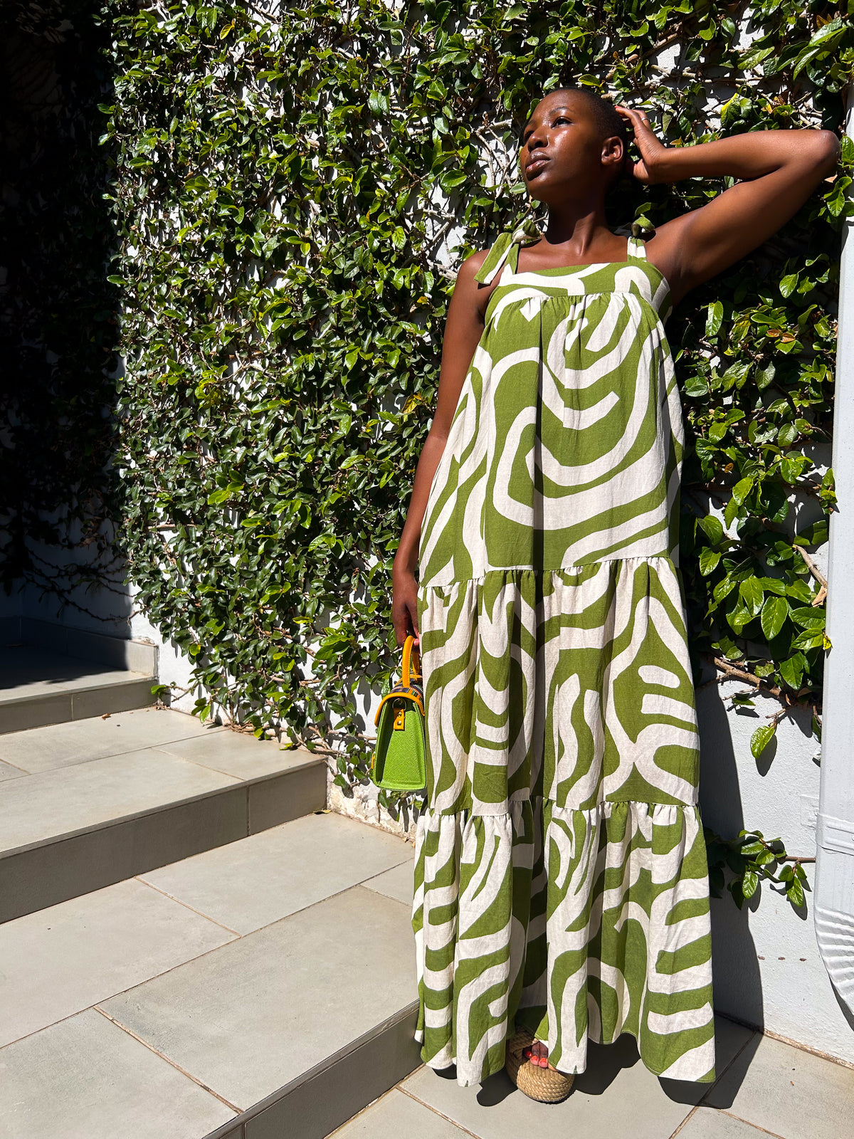 African woman wearing a Ranji Dress in green and white, with a Dr Pachanga handbag. 