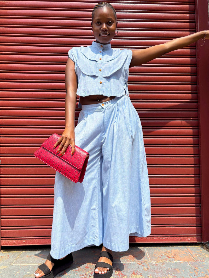 African woman wearing Buhle sky colour pants, holding a Dr Pachanga handbag.