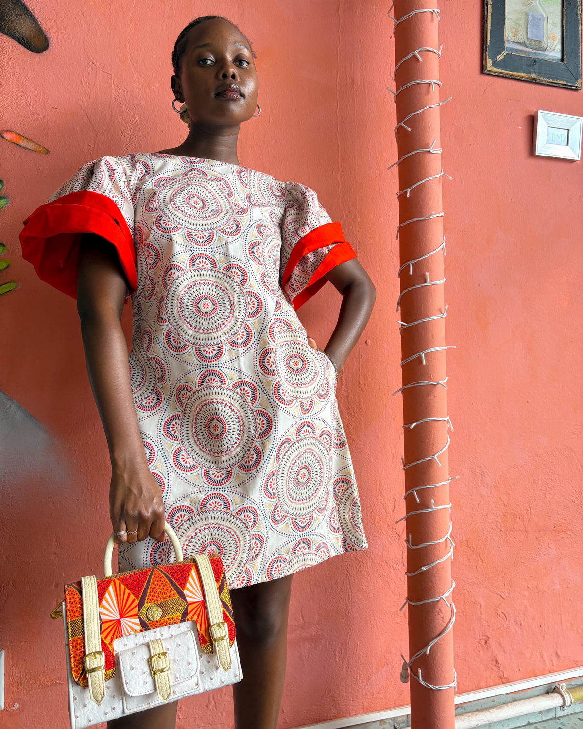 African woman wearing a Sam Dress in off white and red, with a Dr Pachanga handbag.