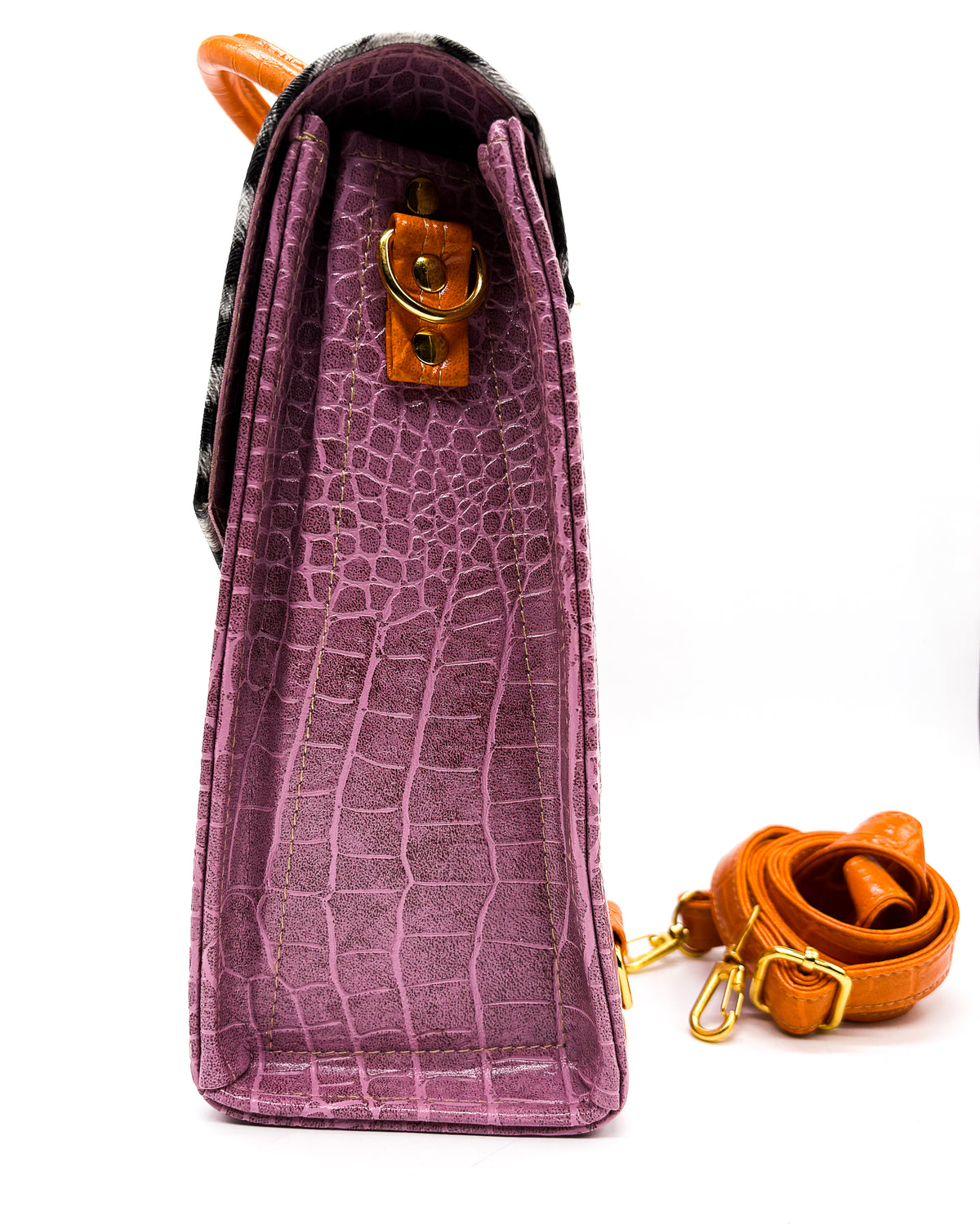 Side view, purple, green and animal print vegan leather handbag, crossbody or backpack with African wax fabric accent, a gold buckle and a magnetic clasp.