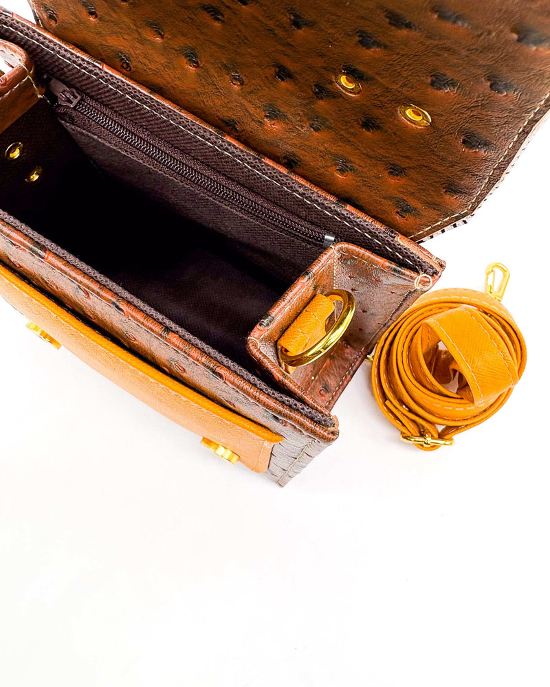 Open, brown vegan leather handbag or crossbody bag with orange accents, gold African Wax fabric inlay, two gold buckles and magnetic clasp.