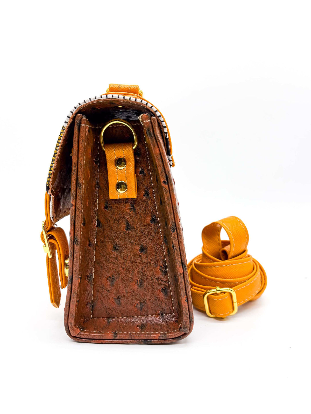 Side view, brown vegan leather handbag or crossbody bag with orange accents, gold African Wax fabric inlay, two gold buckles and magnetic clasp.