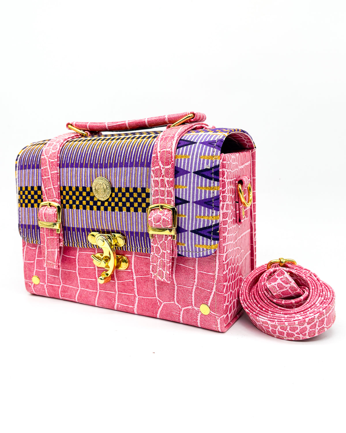 Pink textured vegan leather handbag or crossbody bag with purple and gold African wax fabric inlay, two gold buckles and a gold clasp.