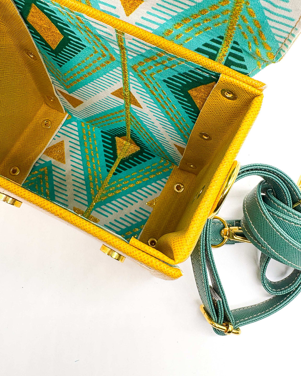 Inside view, yellow and green vegan leather handbag or crossbody bag with African wax fabric interior lining, two gold buckles and a magnetic clasp.